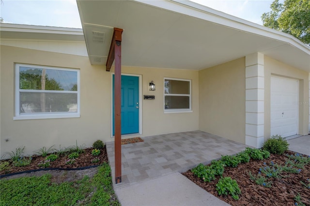 entrance to property with a garage and stucco siding