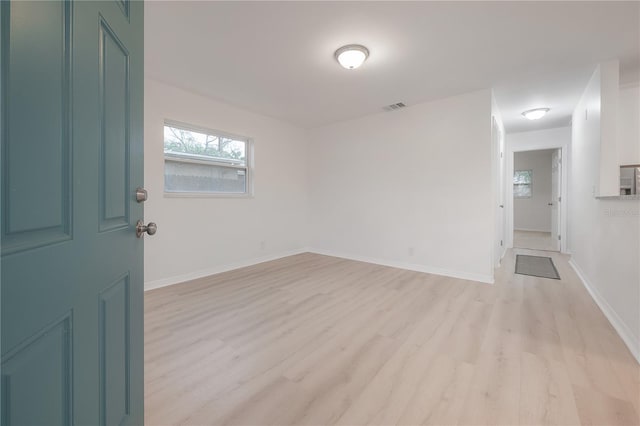 empty room featuring light wood finished floors, visible vents, and baseboards