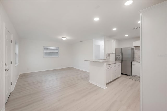 kitchen with visible vents, light wood-style floors, open floor plan, white cabinets, and stainless steel fridge