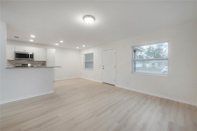 unfurnished living room featuring light wood finished floors, recessed lighting, and baseboards