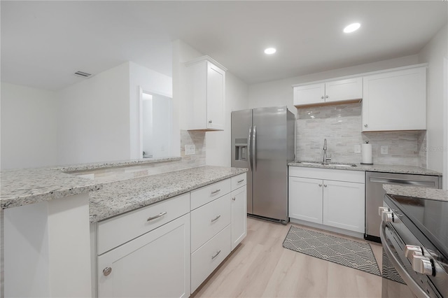 kitchen with light stone counters, stainless steel refrigerator with ice dispenser, a sink, and white cabinets