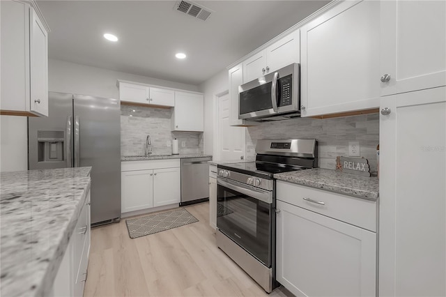 kitchen with light wood-style flooring, a sink, visible vents, white cabinetry, and appliances with stainless steel finishes