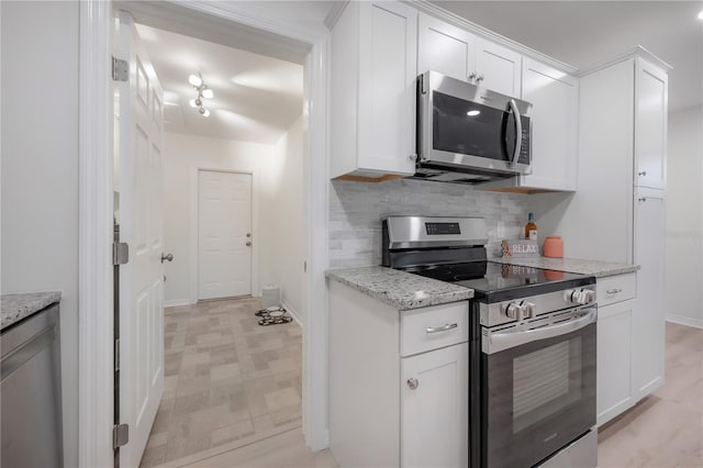 kitchen with baseboards, white cabinets, decorative backsplash, appliances with stainless steel finishes, and light stone countertops