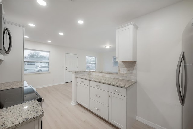 kitchen featuring a wealth of natural light, appliances with stainless steel finishes, light wood finished floors, and white cabinetry