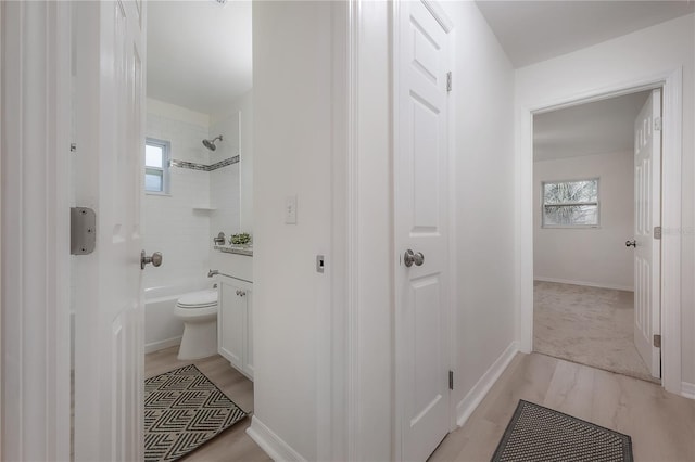 full bath featuring a wealth of natural light, shower / bath combination, baseboards, and wood finished floors