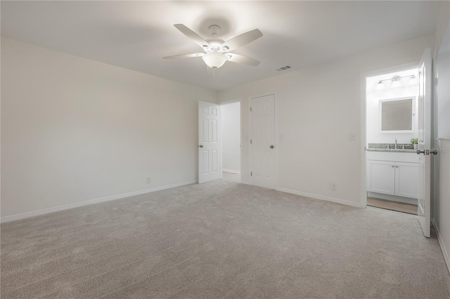 unfurnished bedroom with visible vents, light carpet, a sink, ensuite bath, and baseboards