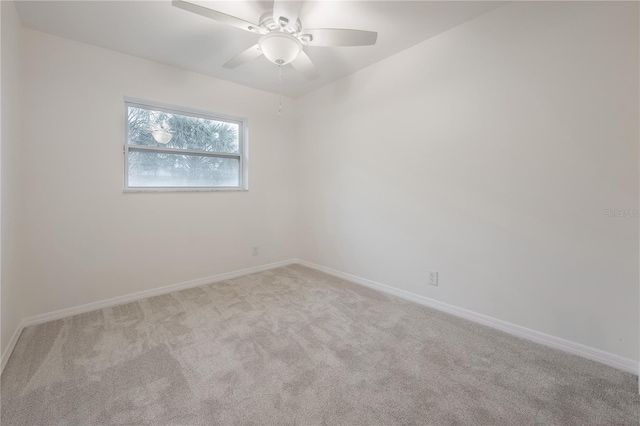 carpeted spare room featuring baseboards and a ceiling fan