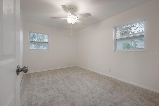 carpeted spare room featuring a ceiling fan and baseboards