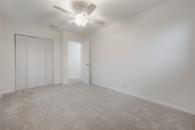 unfurnished bedroom featuring ceiling fan, light carpet, visible vents, baseboards, and a closet