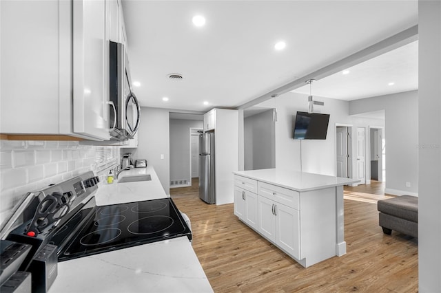 kitchen featuring tasteful backsplash, light wood-style flooring, appliances with stainless steel finishes, white cabinetry, and a sink