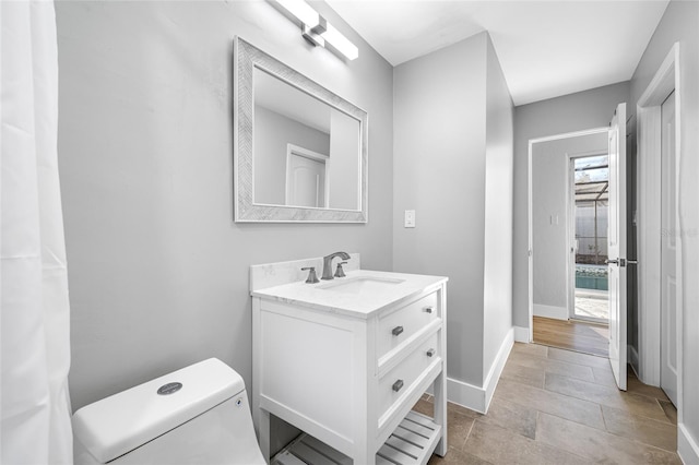 bathroom featuring toilet, vanity, and baseboards