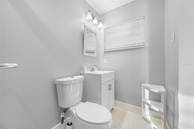 bathroom with toilet, tile patterned floors, baseboards, and vanity