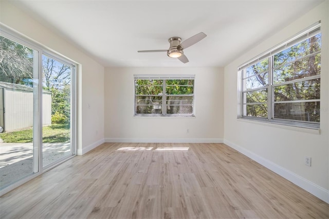 spare room featuring baseboards, light wood-type flooring, and ceiling fan