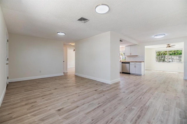 unfurnished living room with visible vents, a ceiling fan, a textured ceiling, light wood finished floors, and baseboards