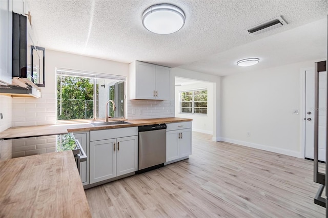 kitchen featuring visible vents, butcher block counters, a wealth of natural light, appliances with stainless steel finishes, and a sink