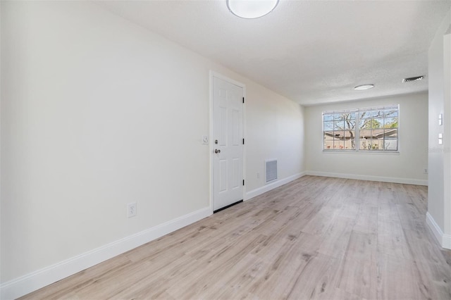 empty room with visible vents, baseboards, a textured ceiling, and light wood-style flooring