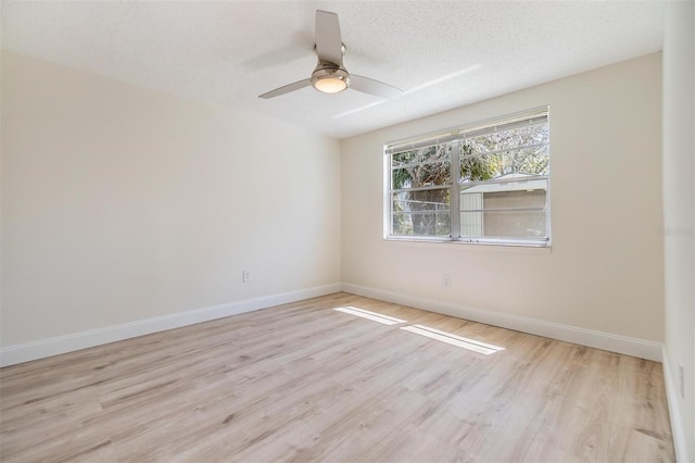 empty room with ceiling fan, baseboards, a textured ceiling, and wood finished floors