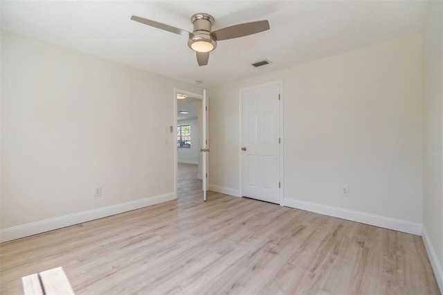 spare room with ceiling fan, visible vents, baseboards, and light wood-style flooring