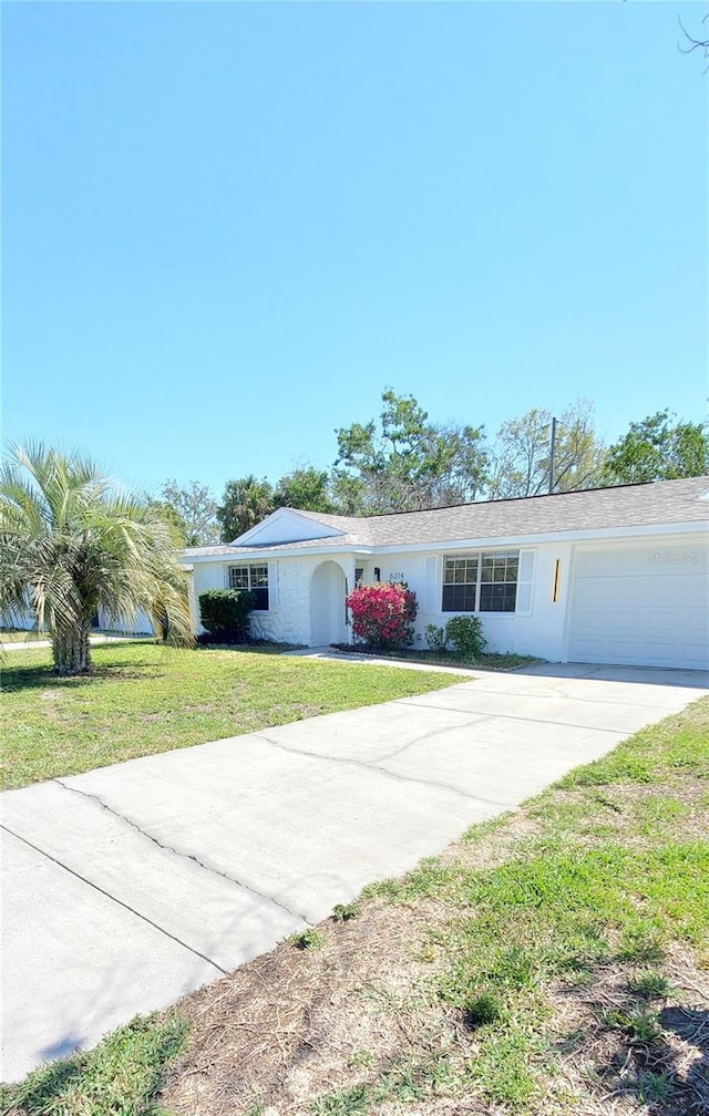 ranch-style house with stucco siding, driveway, a front lawn, and an attached garage