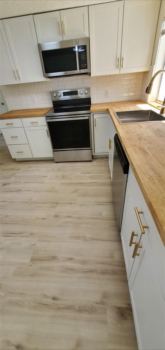 kitchen featuring a sink, stainless steel appliances, tasteful backsplash, and butcher block countertops