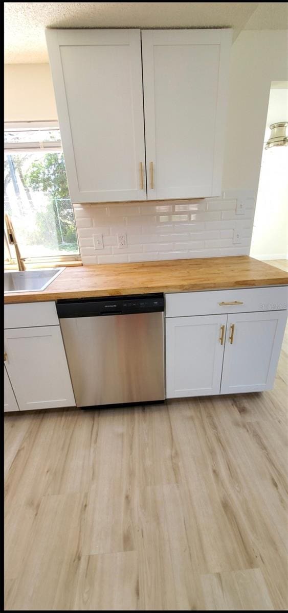 kitchen with butcher block countertops, dishwasher, light wood-style flooring, and white cabinetry