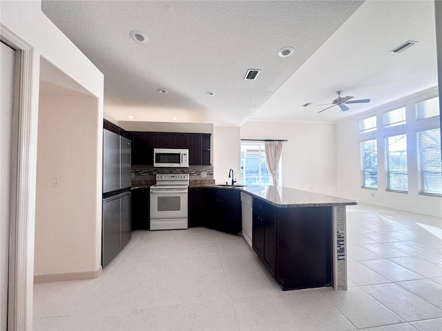 kitchen with white appliances, a sink, visible vents, and dark cabinetry