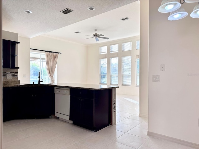 kitchen with a peninsula, visible vents, dark cabinetry, dishwasher, and tasteful backsplash