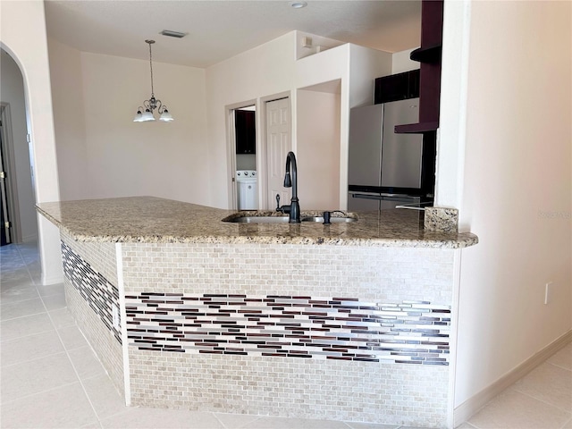 kitchen featuring light tile patterned floors, light stone counters, a sink, and freestanding refrigerator