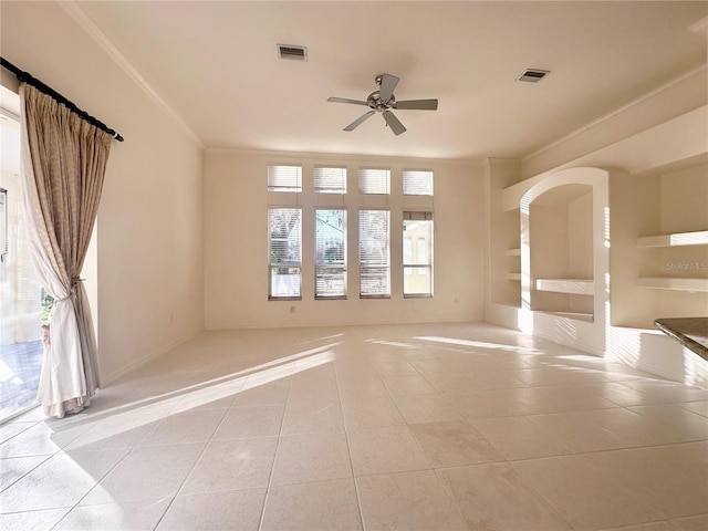 empty room with light tile patterned floors, ceiling fan, visible vents, and crown molding