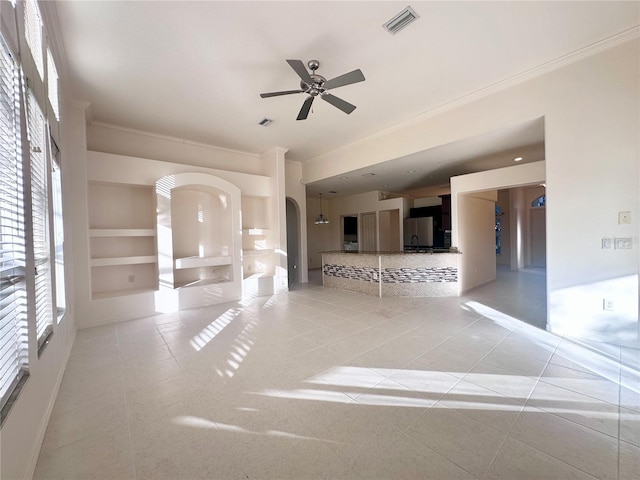 unfurnished living room with arched walkways, crown molding, light tile patterned floors, visible vents, and a ceiling fan