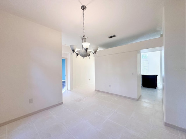 spare room featuring a chandelier, visible vents, and baseboards