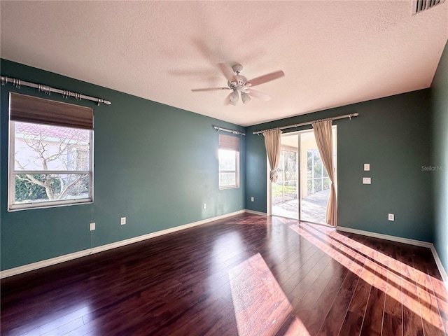 unfurnished room featuring baseboards, visible vents, dark wood-style floors, ceiling fan, and a textured ceiling