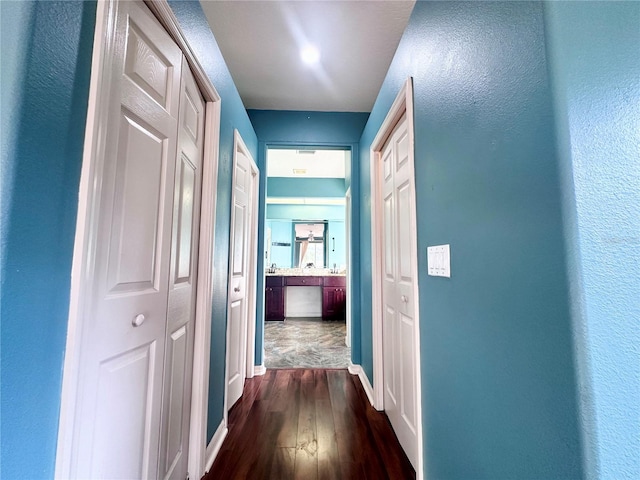 corridor featuring dark wood finished floors and baseboards