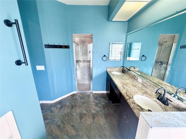 bathroom featuring baseboards, double vanity, a sink, and a shower stall