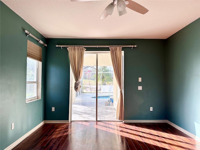 spare room featuring a textured ceiling, ceiling fan, hardwood / wood-style floors, and baseboards