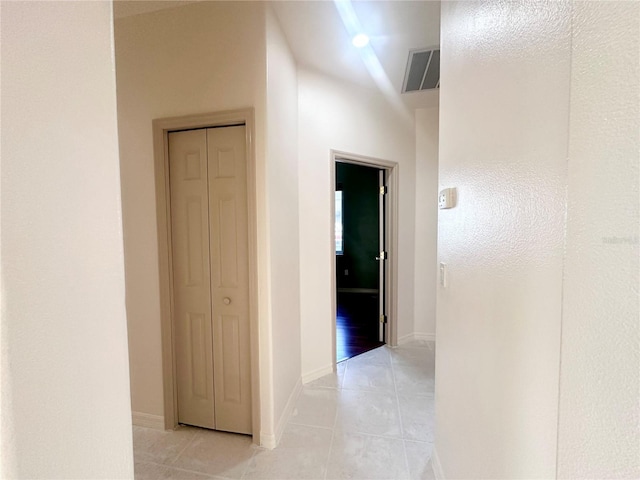 hallway featuring light tile patterned flooring, visible vents, and baseboards