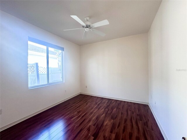 empty room featuring a ceiling fan, dark wood-style flooring, and baseboards