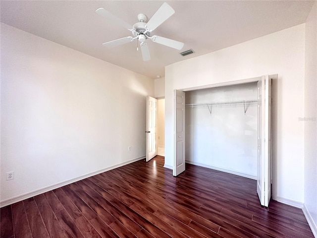 unfurnished bedroom with a closet, visible vents, dark wood finished floors, and baseboards