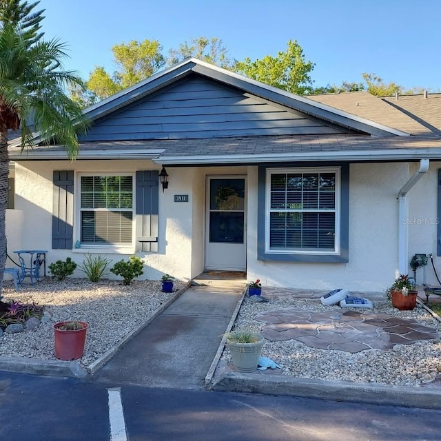 view of front facade with roof with shingles and stucco siding