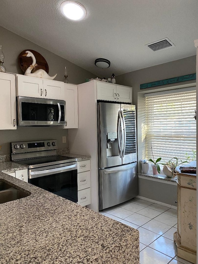 kitchen featuring white cabinetry, visible vents, appliances with stainless steel finishes, and vaulted ceiling