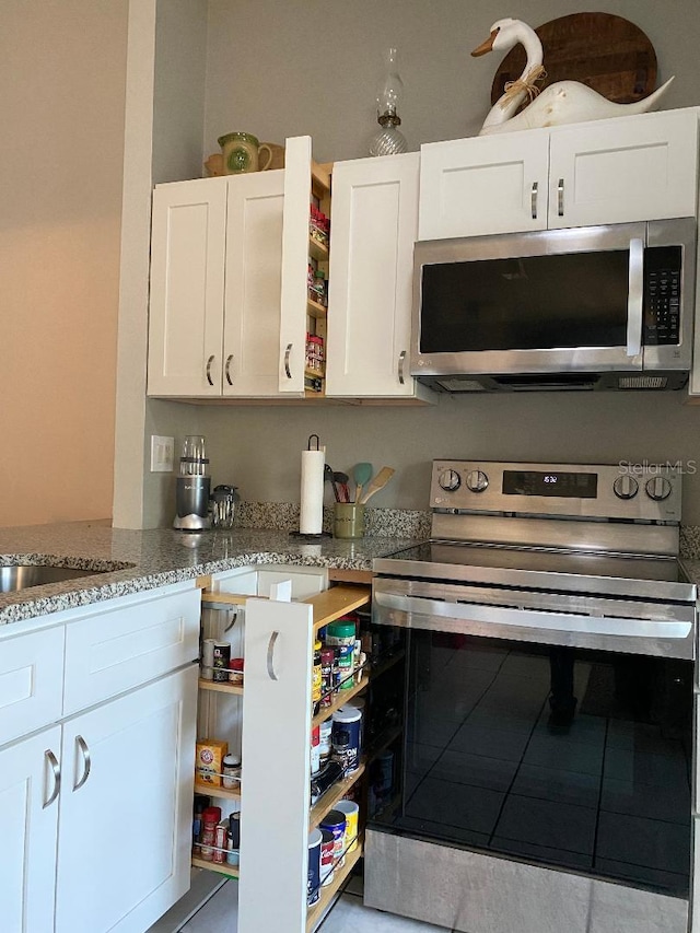 kitchen with open shelves, light stone countertops, white cabinets, and stainless steel appliances