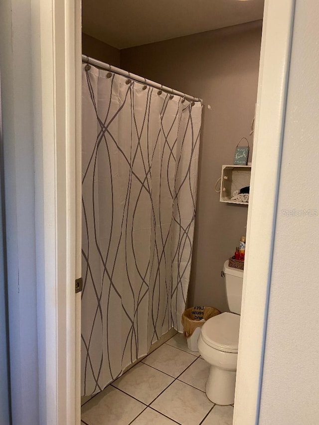 full bath with a shower with shower curtain, toilet, and tile patterned floors