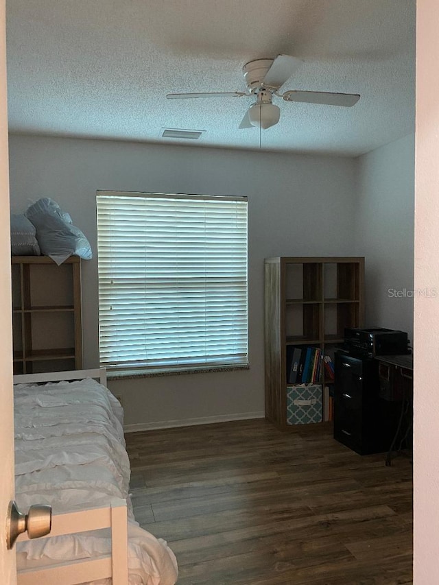 bedroom featuring a textured ceiling, wood finished floors, visible vents, and a ceiling fan