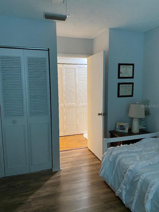 bedroom featuring dark wood-style flooring, visible vents, and a textured ceiling