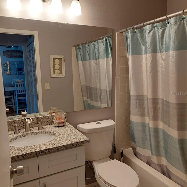 bathroom featuring toilet, shower / bath combo with shower curtain, and vanity