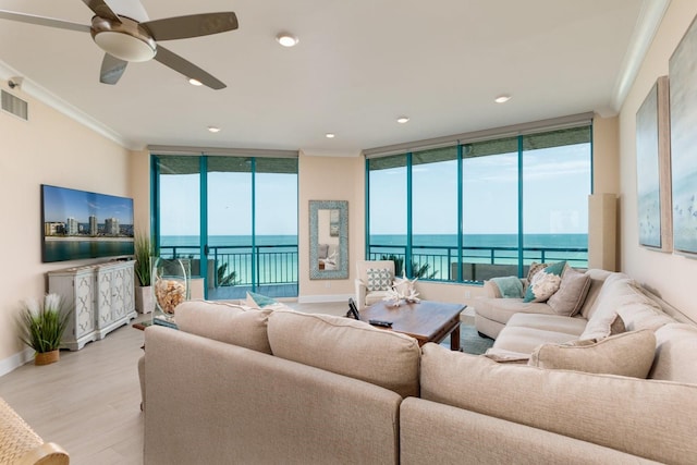 living room with expansive windows, light wood-style floors, a water view, and crown molding