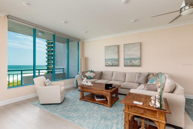 living area with ornamental molding, ceiling fan, baseboards, and wood finished floors