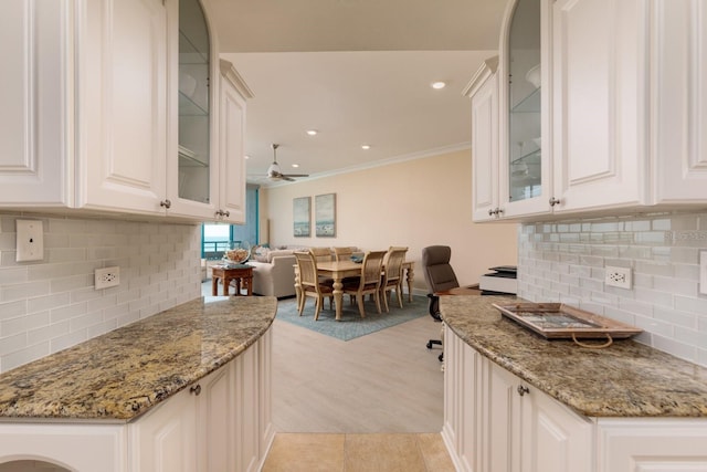 kitchen featuring open floor plan, light stone counters, a ceiling fan, and white cabinetry