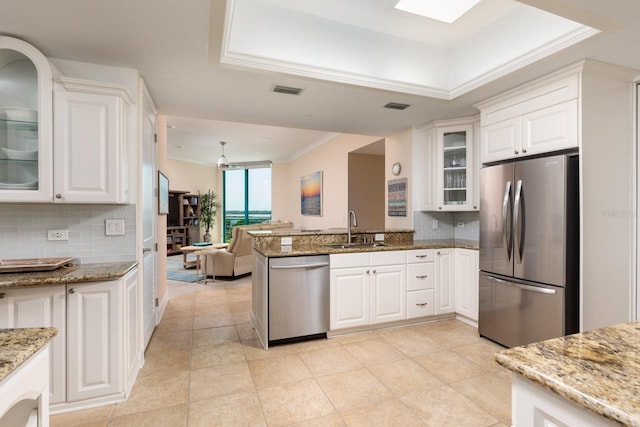 kitchen with white cabinets, ornamental molding, stainless steel appliances, and a sink