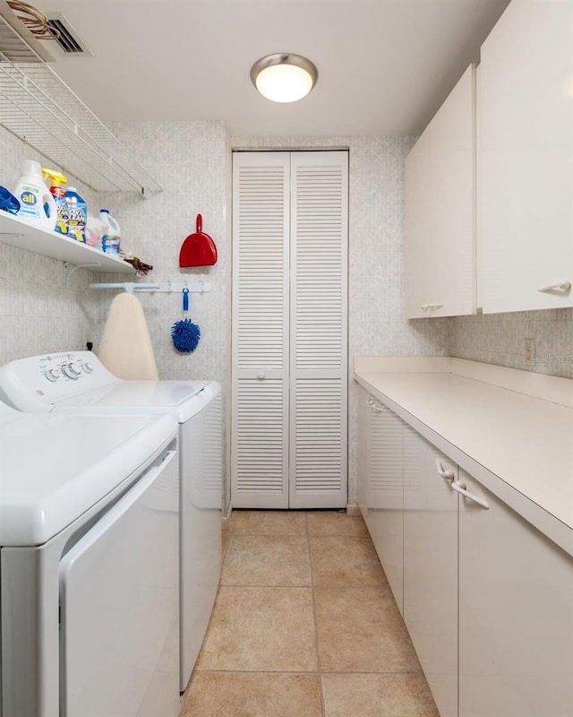 clothes washing area featuring visible vents, light tile patterned flooring, independent washer and dryer, and cabinet space